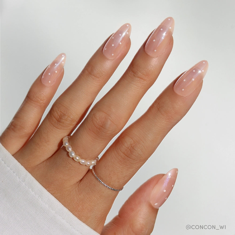 Hand with pink nail polish and a pearl ring on a light background